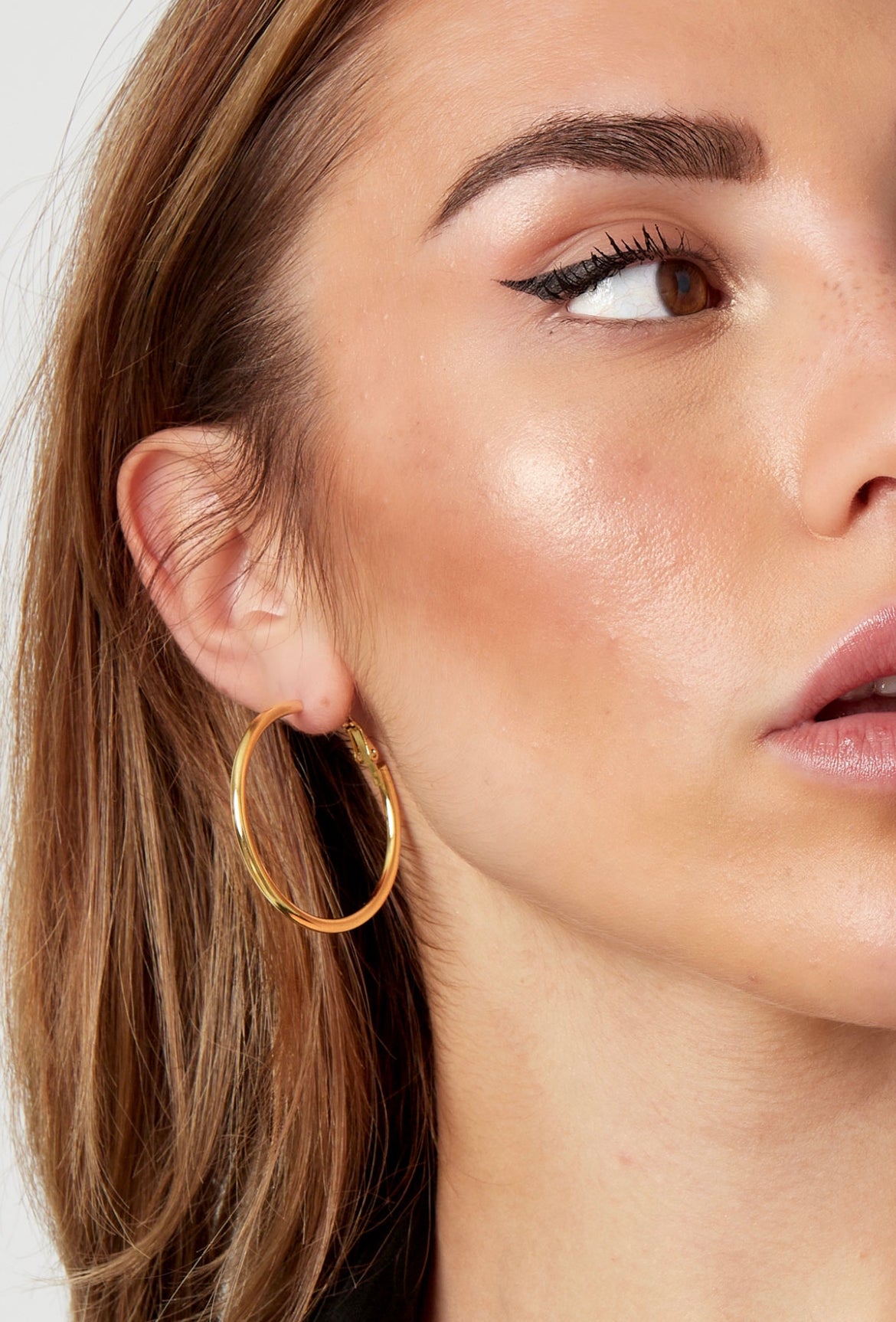 Gold hoop earrings worn on ear close-up