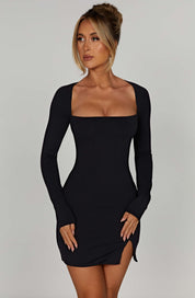 Black mini dress with square neckline and front side slit, side view with high heels