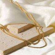 Gold-colored layered necklace on stone blocks overhead view