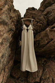 Cream maxi dress with floral detail hanging on rocks