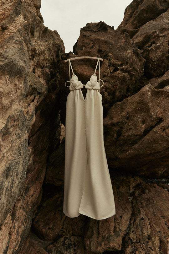 Cream maxi dress with floral detail hanging on rocks