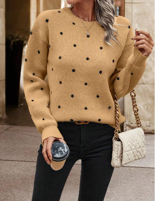 Beige knit sweater with black polka dots holding coffee cup