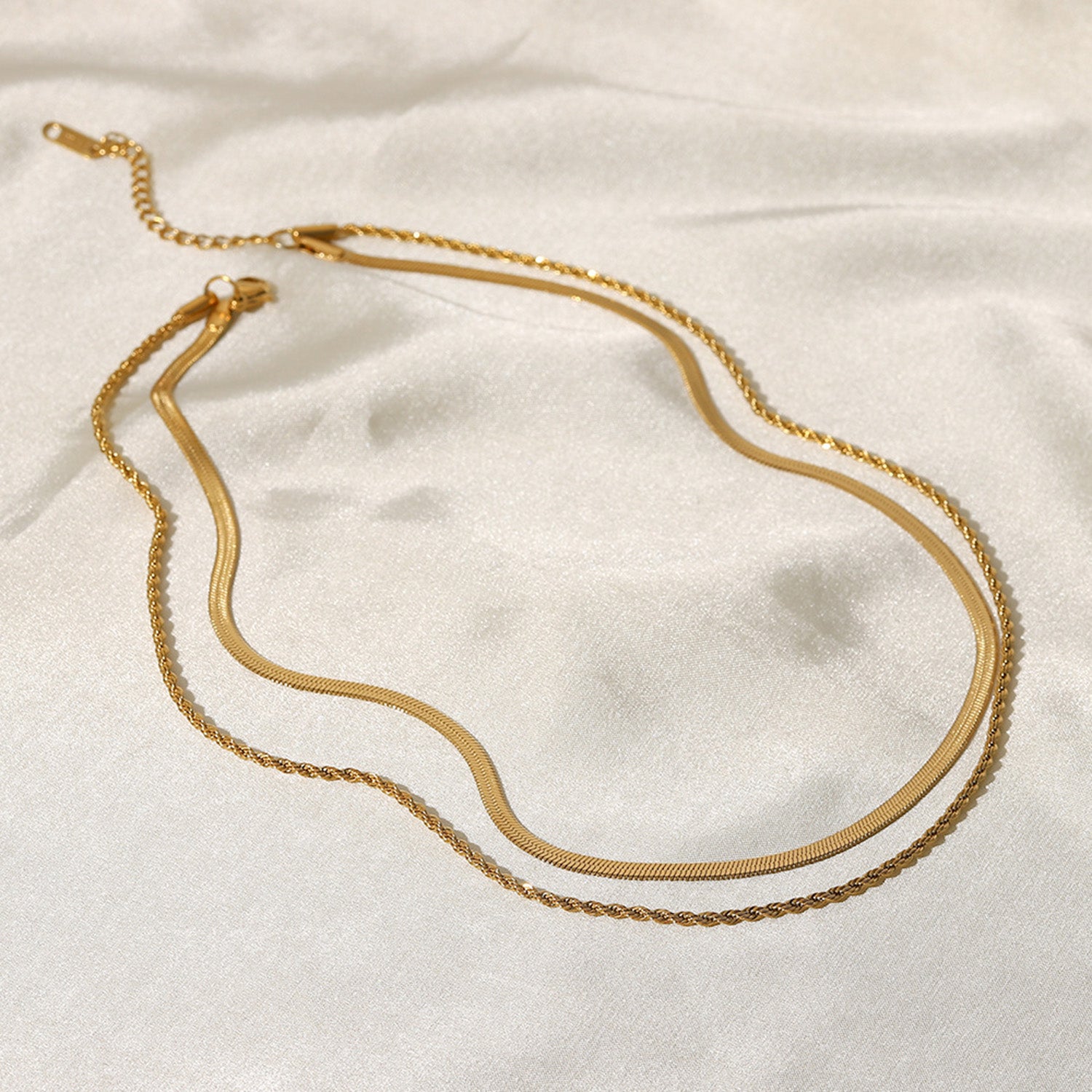 Gold-colored layered necklace on fabric background side view