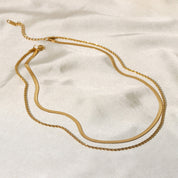 Gold-colored layered necklace on fabric background side view