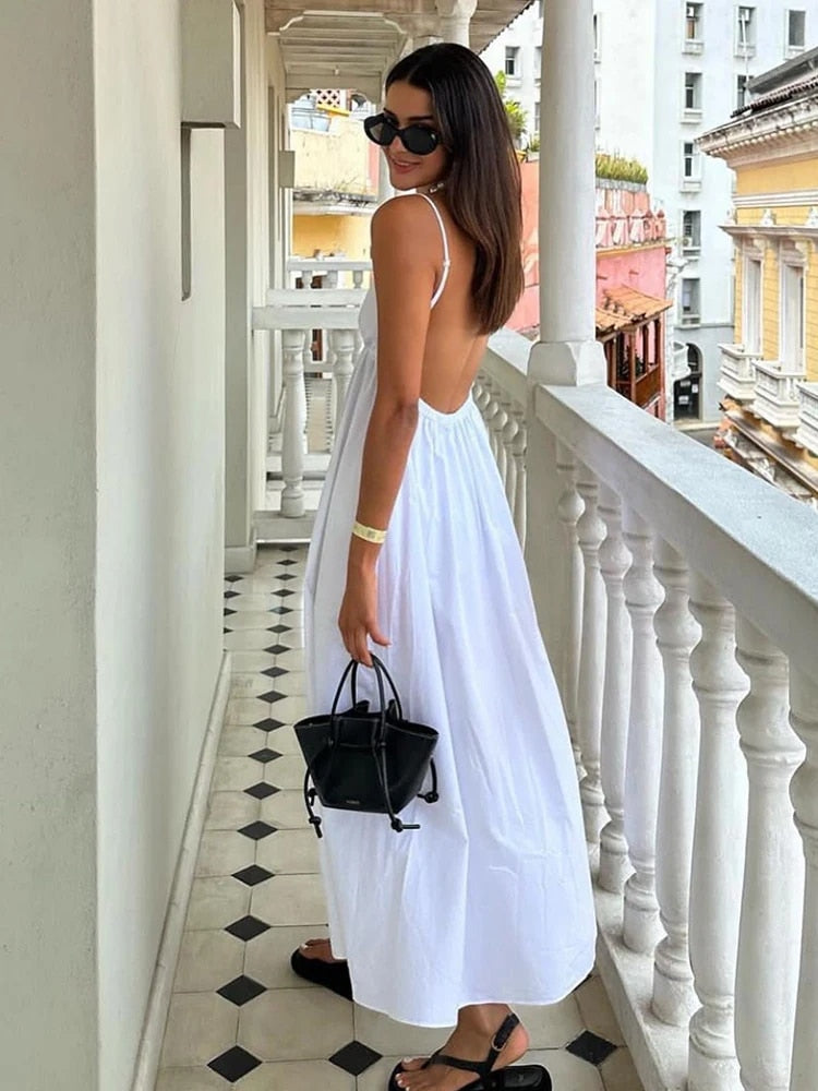 White maxi dress with spaghetti straps and open back, back view on balcony