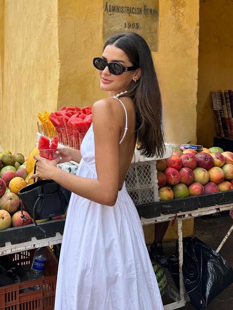 White maxi dress with spaghetti straps, side view near fruit stand