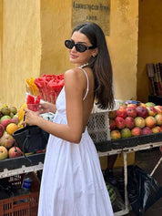 White maxi dress with spaghetti straps, side view near fruit stand