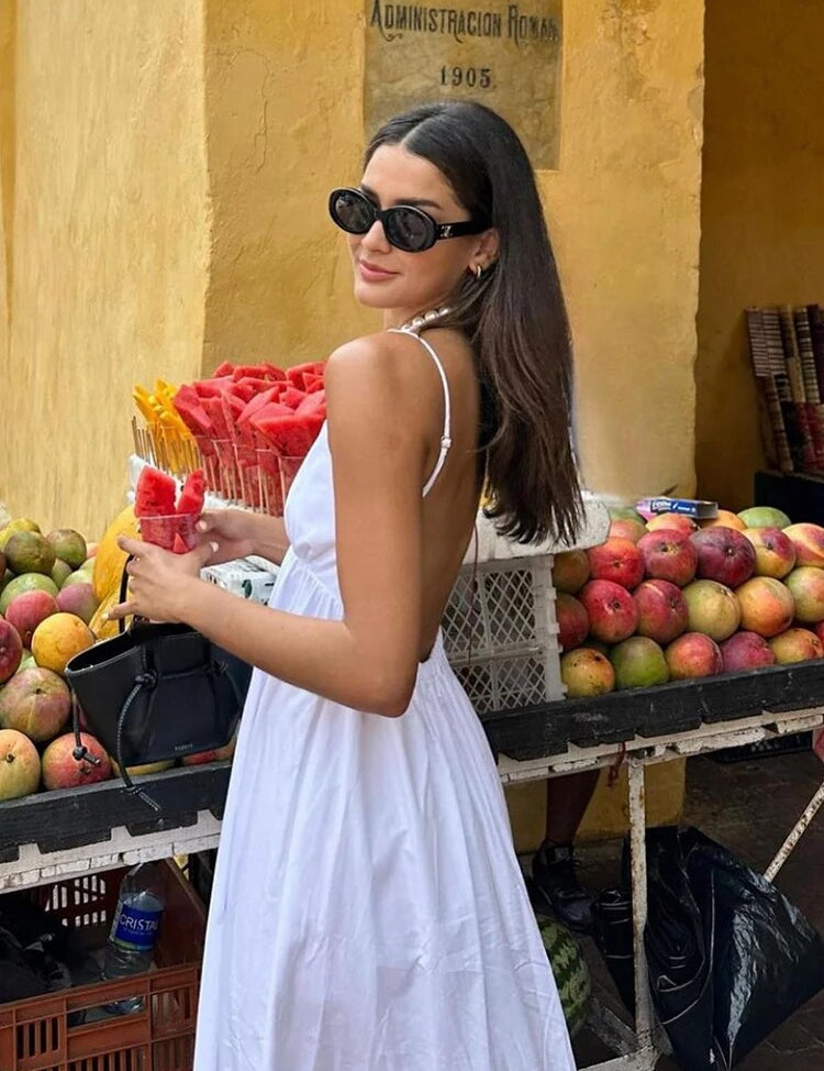 White maxi dress with spaghetti straps, side view near fruit stand