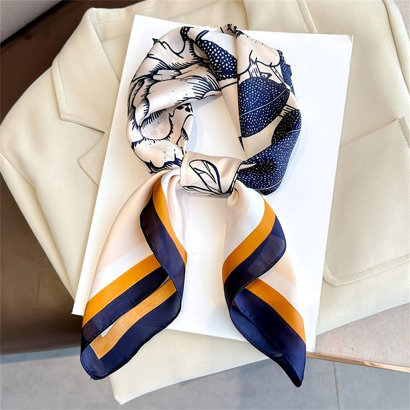 Silk scarf with floral and bird print, blue and orange border, folded on white background