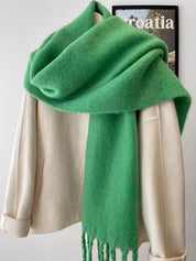 Green scarf with fringe draped over mannequin front view
