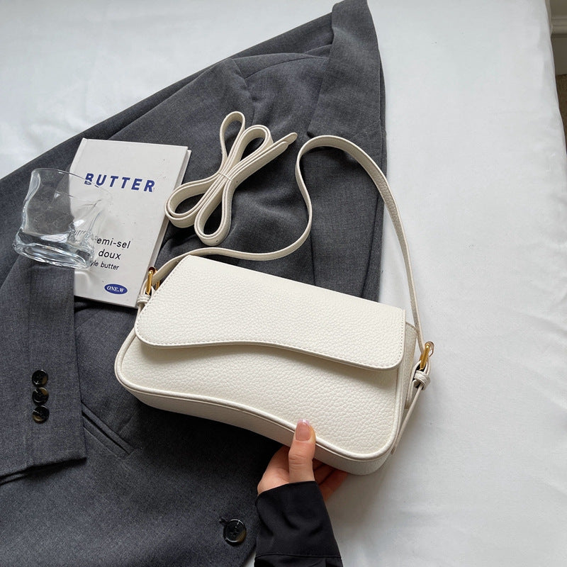 White shoulder bag with textured leather and gold hardware held in hand