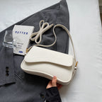 White shoulder bag with textured leather and gold hardware held in hand