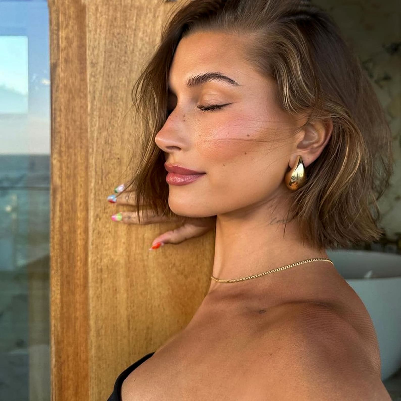 Gold sculptural hoop earrings worn on ear, front view