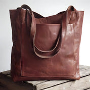 Brown leather tote bag with exterior pocket angled view