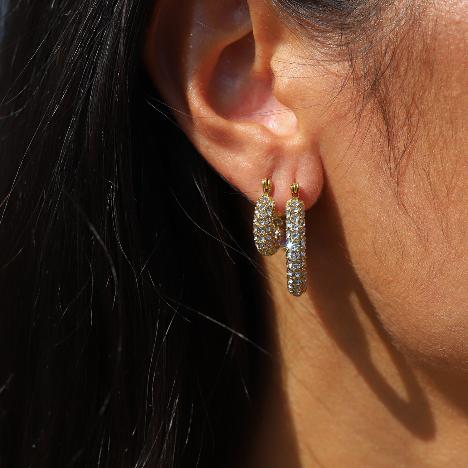 Gold hoop earrings with pave crystals worn on ear angled view