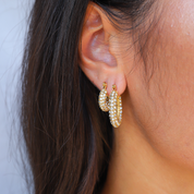 Gold hoop earrings with pave crystals worn on ear close-up