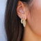 Gold hoop earrings with pave crystals worn on ear close-up