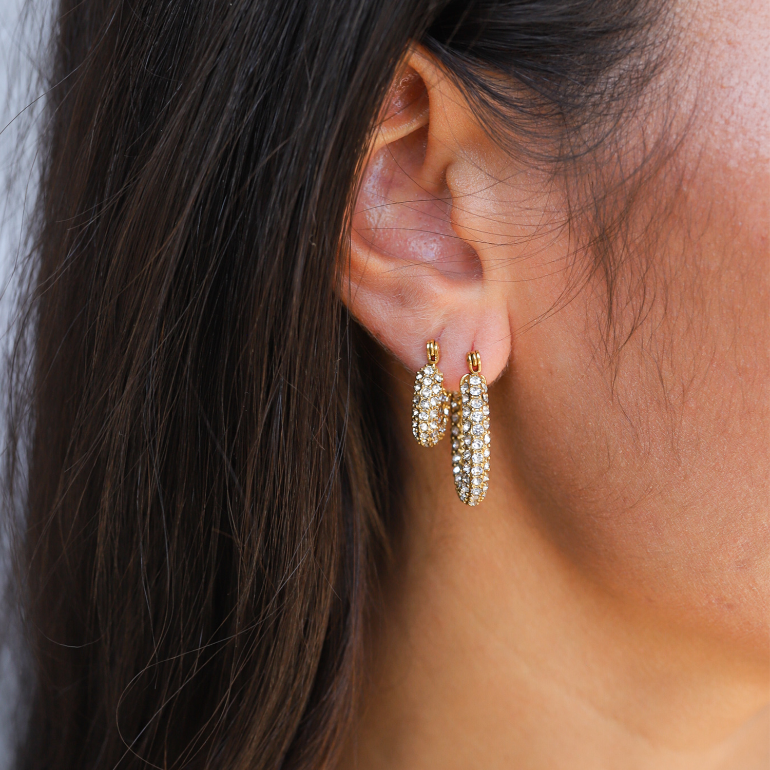 Gold hoop earrings with pave crystals worn on ear