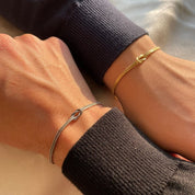 Gold and silver armbands with knot charms on wrists front view