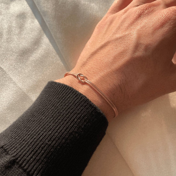 Rose gold armband with knot charm on wrist close-up
