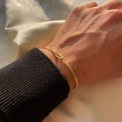 Gold armband with knot charm on wrist front view