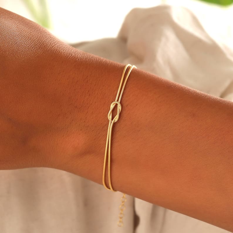 Gold armband with knot charm on wrist front view