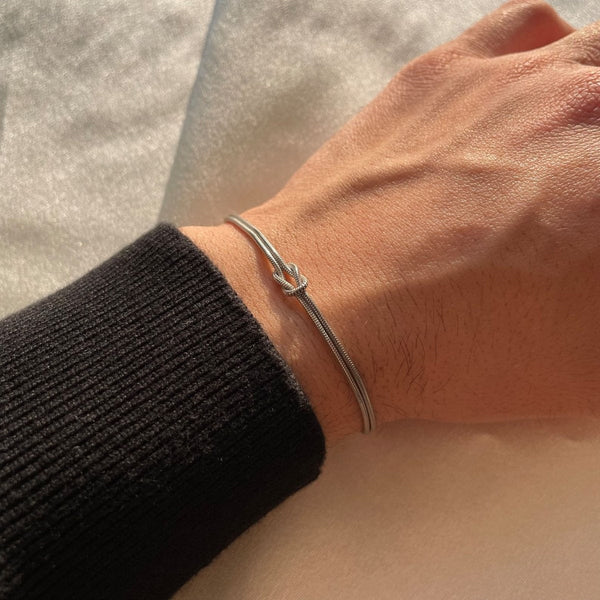 Silver armband with knot charm on wrist close-up