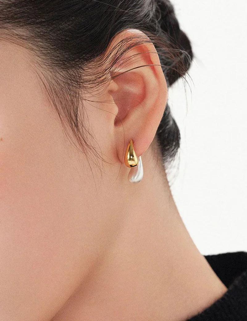 Gold and silver earrings worn on ear close-up