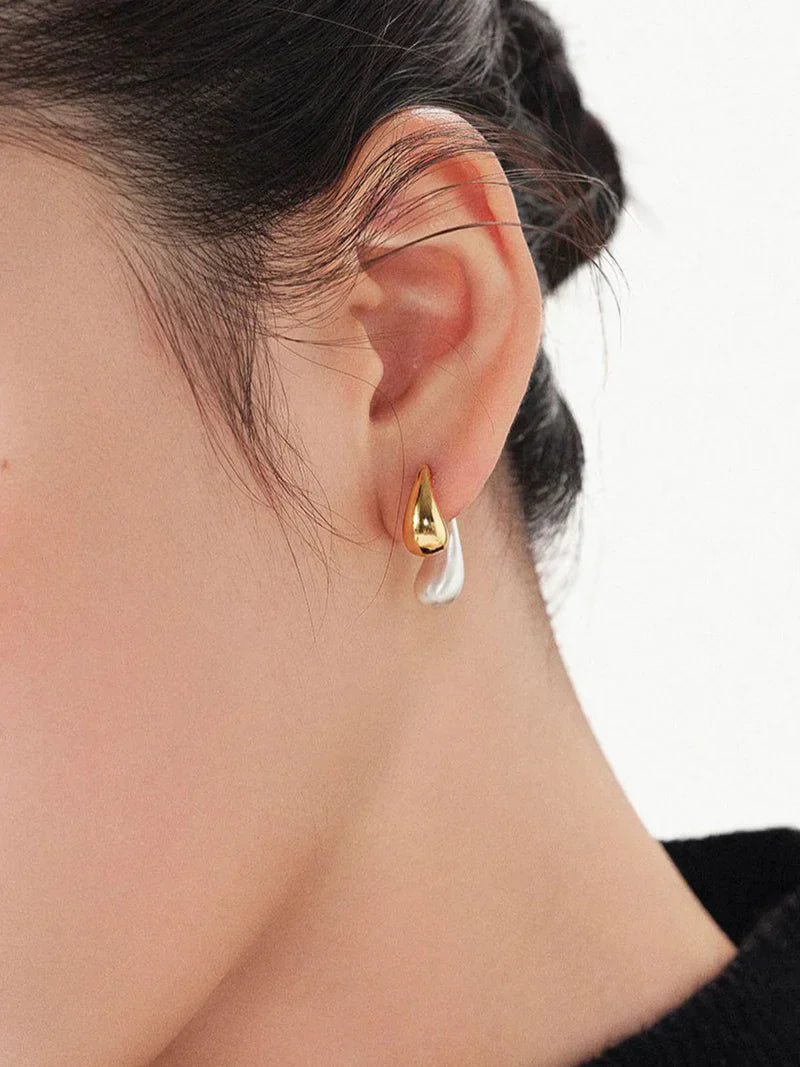 Gold and silver earrings worn on ear close-up