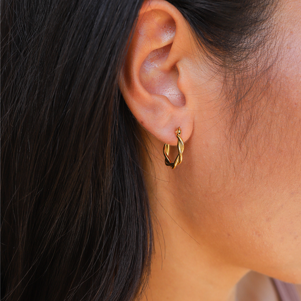 Gold hoop earrings worn on ear, side view